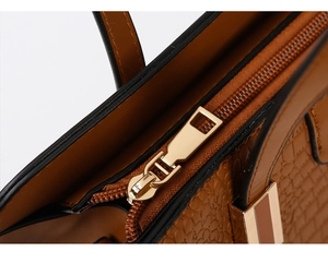 Close-up of textured brown leather handbag featuring high-quality gold metal zipper details