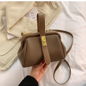 Detail of vintage brown pebble leather handbag with gold metal lock and shoulder strap