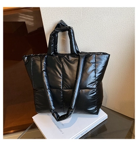 Detail of black quilted puffer tote bag with dual straps on a minimalist display