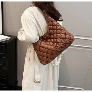 Brown quilted tote bag shown from a side view on a shoulder in a minimalist setting
