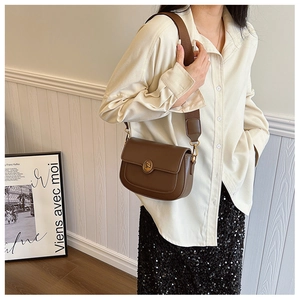 Detail of vintage brown saddle bag with gold metal buckle and canvas wide strap