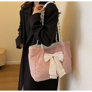 Detailed close-up of a pink plush tote bag with a white silk bow on a model