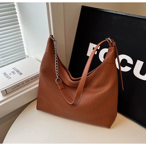 Détail de la texture en cuir plissé marron et bandoulière chaîne du sac cabas