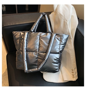 Detail of silver metallic quilted puffer tote bag featuring wide padded handles