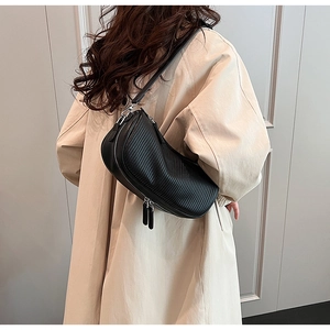 Detail of black semi-circle crossbody bag with vertical texture and adjustable strap