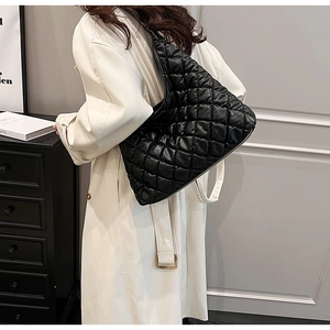 Close-up of black quilted shoulder bag with padded rhombic pattern and chain strap