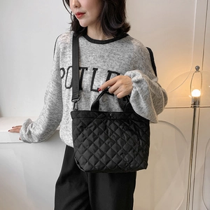 Borsa tote nera trapuntata alla moda con ampia tracolla indossata da una modella