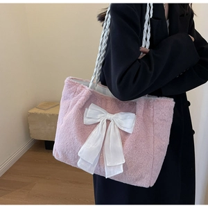 Detail of soft pink plush tote bag featuring a large white bow and woven leather handle