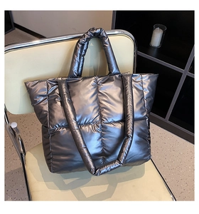 Detail of silver metallic quilted tote bag with large square stitching on leather chair