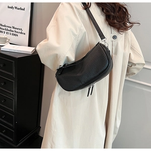 Detail of black pleated crescent shoulder bag with silver hardware and leather strap