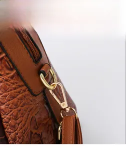 Detail of brown crocodile pattern leather with gold metal D-ring and lobster clasp hardware