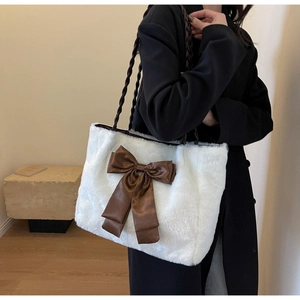 Close-up of white faux fur tote bag featuring a large dark brown satin bow detail