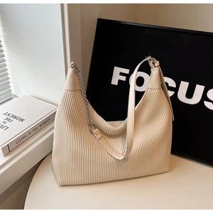 Détail du sac hobo crème avec texture plissée verticale et bandoulière en chaîne argentée