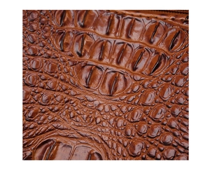 Macro detail of dark brown crocodile embossed leather with glossy texture and scale pattern