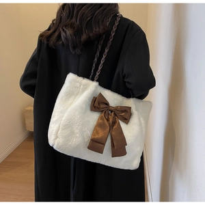 Detail of white faux fur tote bag with a large brown satin bow and braided strap