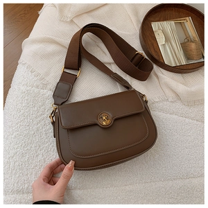 Detailed close-up of dark brown vintage crossbody bag with golden embossed hardware buckle