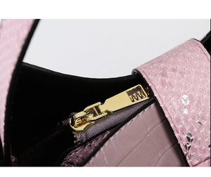 Macro shot of pink python pattern and purple crocodile texture stitching on bucket bag
