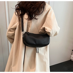 Detail of black crescent crossbody bag with vertical pleated texture and silver zippers