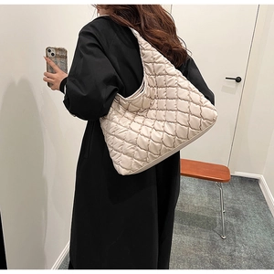 Detail of beige quilted puffer shoulder bag showing fluffy texture and chain strap