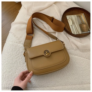 Close-up of camel leather crossbody bag with vintage relief buckle and wide woven strap