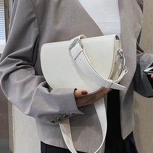 Sacoche selle blanc crème avec large bandoulière, portée par un mannequin en blazer