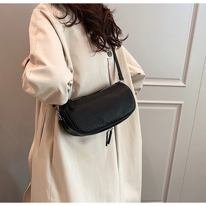 Detail of black pleated cylindrical crossbody bag showing texture and metal zippers