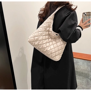 Detailed close-up of quilted ivory hobo bag showing textured satin finish and shoulder fit