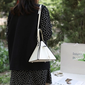 Détails du sac pyramide en cuir blanc avec clous de fond en métal et bordures noires