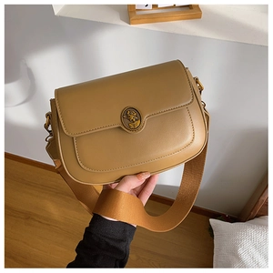 Detail of caramel leather crossbody bag with vintage gold emblem buckle and woven strap