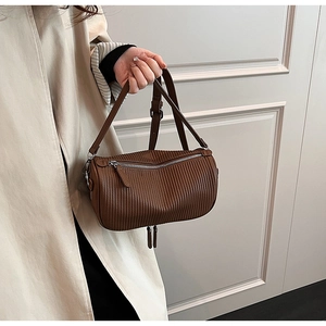 Detailed view of brown cylindrical pillow bag featuring vertical pleated texture and silver zipper