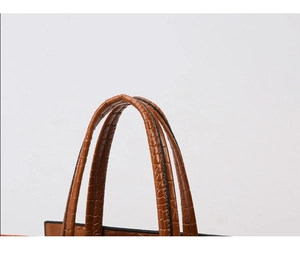 Dettaglio dei manici marroni con trama a coccodrillo e cuciture di una borsa in PU