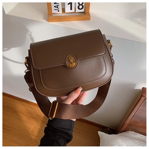 Detailed close-up of dark brown vintage PU leather bag with retro metal relief badge decoration
