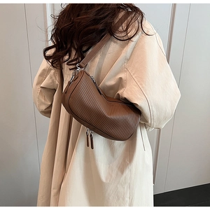 Vertical pleated texture detail on a brown crescent-shaped crossbody shoulder bag