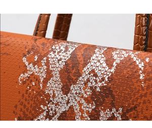 Detail of orange snake and crocodile texture patchwork on a women's handbag