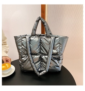 Close-up of quilted silver down tote bag with metallic texture on a black table