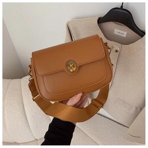 Detail of caramel brown crossbody bag with gold portrait buckle and canvas strap
