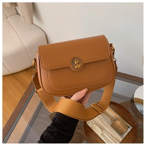 Close-up of vintage brown leather handbag with gold lady relief buckle and wide strap