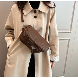 Close-up of textured dark brown leather crossbody bag with dual zipper and silver hardware