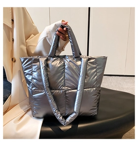 Detailed close-up of quilted silver puffer tote bag with metallic texture and shoulder strap