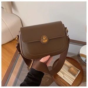 Close-up of vintage brown leather bag with a gold portrait coin buckle and wide strap