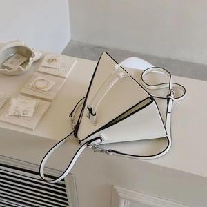 Détail du sac à main triangulaire blanc avec nœuds décoratifs et bandoulière réglable