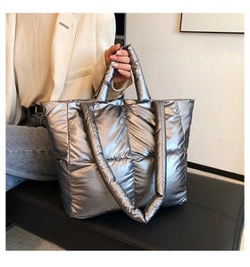 Close-up of metallic silver quilted puffer tote bag with handles and shoulder strap