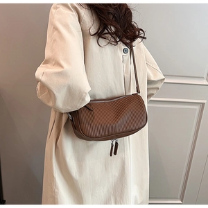 Macro shot of brown crossbody bag featuring vertical pleats and silver zipper detailing