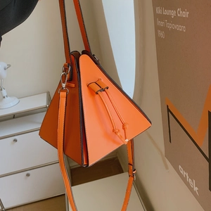 Détail du sac à main triangulaire orange avec boucles argentées et fermeture par cordon