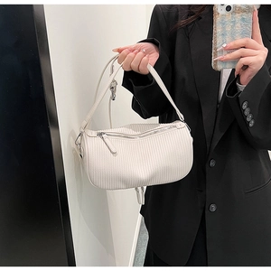 Close-up of white quilted cylinder bag with vertical pleats and silver hardware details