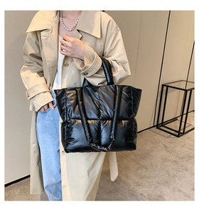 Detailed view of black quilted puffer tote bag on model for size and capacity reference