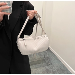 Close-up of a white textured barrel bag with silver zipper and adjustable strap detail