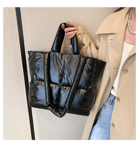 Detailed view of black quilted down tote bag worn by model over a beige trench coat