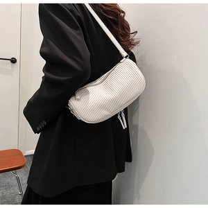 Detail of white pleated crescent shoulder bag featuring vertical texture and sleek zipper