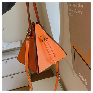 Détail du sac triangulaire orange avec fermeture à cordon et crochet métallique